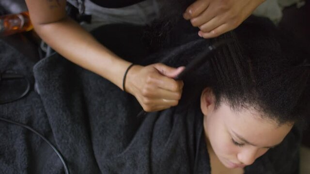 Top down view of young girl of mixed ethnicity having her hair combed and blow-dried 