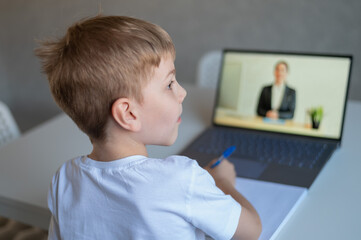 The boy communicates with a female teacher on a laptop webcam. Online lesson. Distance education in quarantine. A schoolboy is studying at home in the epidemic of coronavirus.