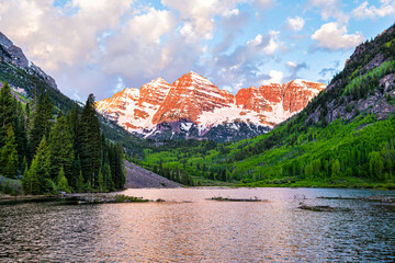 Maroon Bells in Aspen, Colorado with clouds in blue sky at sunrise and rocky mountain peak lake...