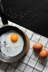 Culinary background with fried eggs in a pan, eggs, peas pepper on a white checkered tablecloth. Culinary concept. the process of cooking eggs. Illustration for cookbook.