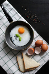 Culinary background with fried eggs in a pan, eggs, peas pepper on a white checkered tablecloth. Culinary concept. the process of cooking eggs. Illustration for cookbook.