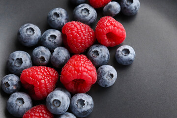 Background with ripe and bright raspberries and blueberries. Berry mix. Heart-shaped raspberries. Proper and healthy nutrition. Design for advertising and books of juices, jams, dessert. Ingredient.
