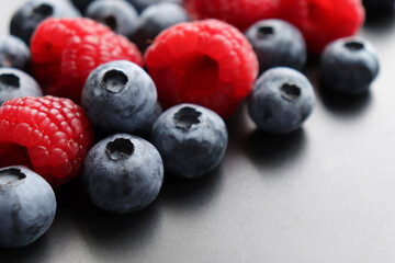 Background with ripe and bright raspberries and blueberries. Berry mix. Heart-shaped raspberries. Proper and healthy nutrition. Design for advertising and books of juices, jams, dessert. Ingredient.
