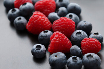 Background with ripe and bright raspberries and blueberries. Berry mix. Heart-shaped raspberries. Proper and healthy nutrition. Design for advertising and books of juices, jams, dessert. Ingredient.