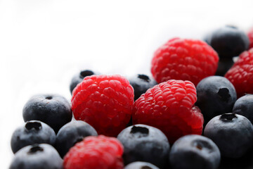 Background with ripe and bright raspberries and blueberries. Berry mix. Heart-shaped raspberries. Proper and healthy nutrition. Design for advertising and books of juices, jams, dessert. Ingredient.