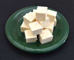Tofu cubes on plate isolated on black background