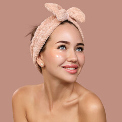 contented smile of a young woman with clean skin and a bandage on her head. The concept of skin care around the eyes. Copycpase Pink background