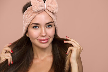 bright woman with a bow on her long straight hair. Smiling on pink background, showing hairstyle....