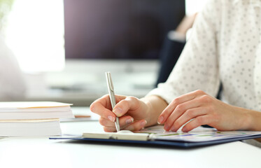 Female hand holding silver pen working with financial document closeup