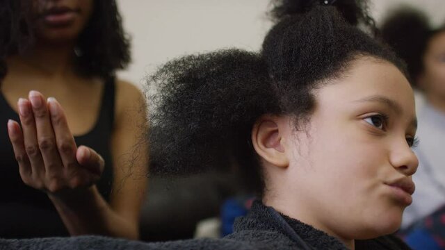 Close up portrait of young girl with afro hair having her hair oiled and styled