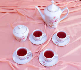 cup of tea and teapot on pink background