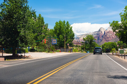 Springdale, USA - August 5, 2019: Zion National Park Road In Utah And Cars In Road Traffic Point Of View Driving In City With Restaurant Shop Stores Sign