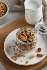 homemade granola with nuts in a glass jar on a wooden board. healthy breakfast concept, vegetarian breakfast.