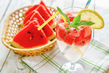 fresh summer cool drink with watermelon slices, mint and lemon on a wooden background,