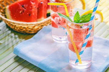 fresh summer cool drink with watermelon slices, mint and lemon on a wooden bamboo background