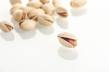 Pistachios on a white glass surface.