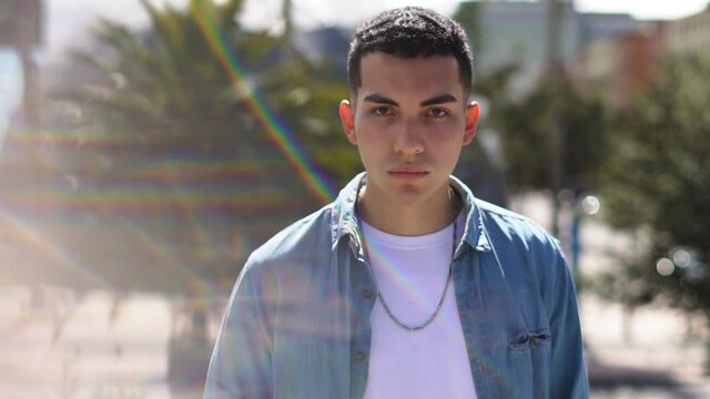 Retrato de hombre joven caucaiso con fonde de naturaleza sube el rostro mirando fijamente a la c&aacute;mara, en una ma&ntilde;ana soleada.