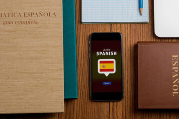 Learn Spanish app and textbooks on wooden table