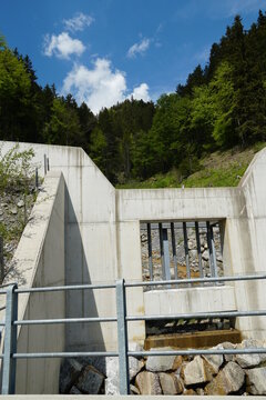 Concrete wall and netal grid protecting the forest brook basin and the valley from dtobes coming with strong stream when snow melts in the Alps. Region Engelberg in Switzerland.