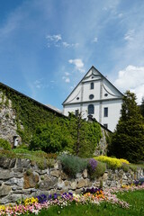 Fototapeta na wymiar Facade of the church belonging to monastery and a wall surrounding the terrain of the monastery in Engelberg, Switzerland. The wall is covered by decorative vegetation.
