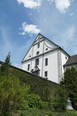 Fototapeta premium Facade of church belonging to monastery from behind in Engelberg, Switzerland. The wall, covered with plants, surrounding terrain of the monastery.