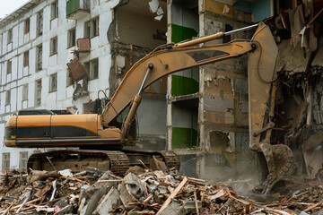 Demolition of a five-story apartment building recognized as emergency housing, close-up of an excavator bucket collects construction waste