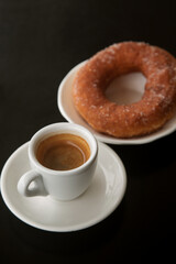doughnut in sugar on a plate and a Cup of espresso coffee, close-up