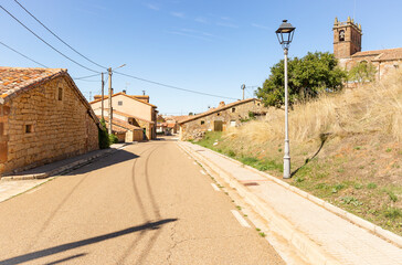 a paved road passing through Revilla del Campo town, province of Burgos, Castile and Leon, Spain