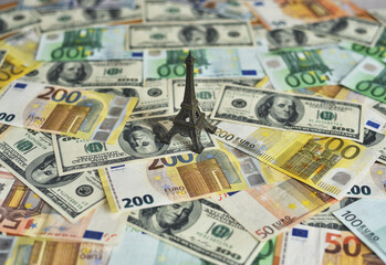 Eiffel tower on a table with money. Figurine on dollar and euro banknotes. Travel and money concept