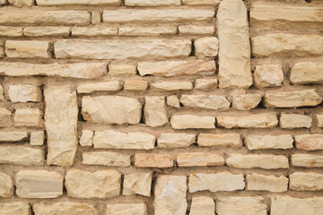 wall of stacked stones in beige-brown tones, texture