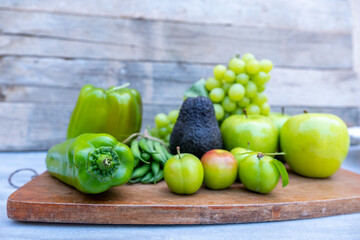 Green vegetables and fruits on a chopping board
