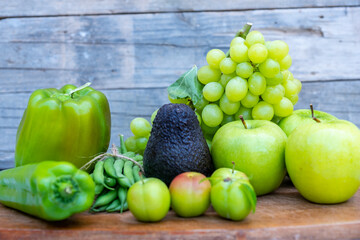 Green vegetables and fruits on a chopping board