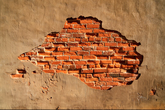 A Break In The Stucco Reveals The Red Bricks Behind It.