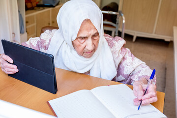 Fototapeta na wymiar Old woman portrait studying ,writing and learning using tablet a