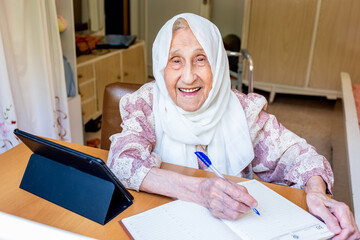 Old woman portrait studying ,writing and learning using tablet a