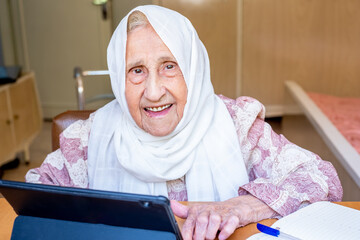 Portrait of senior Arabic woman using electronic tablet at home