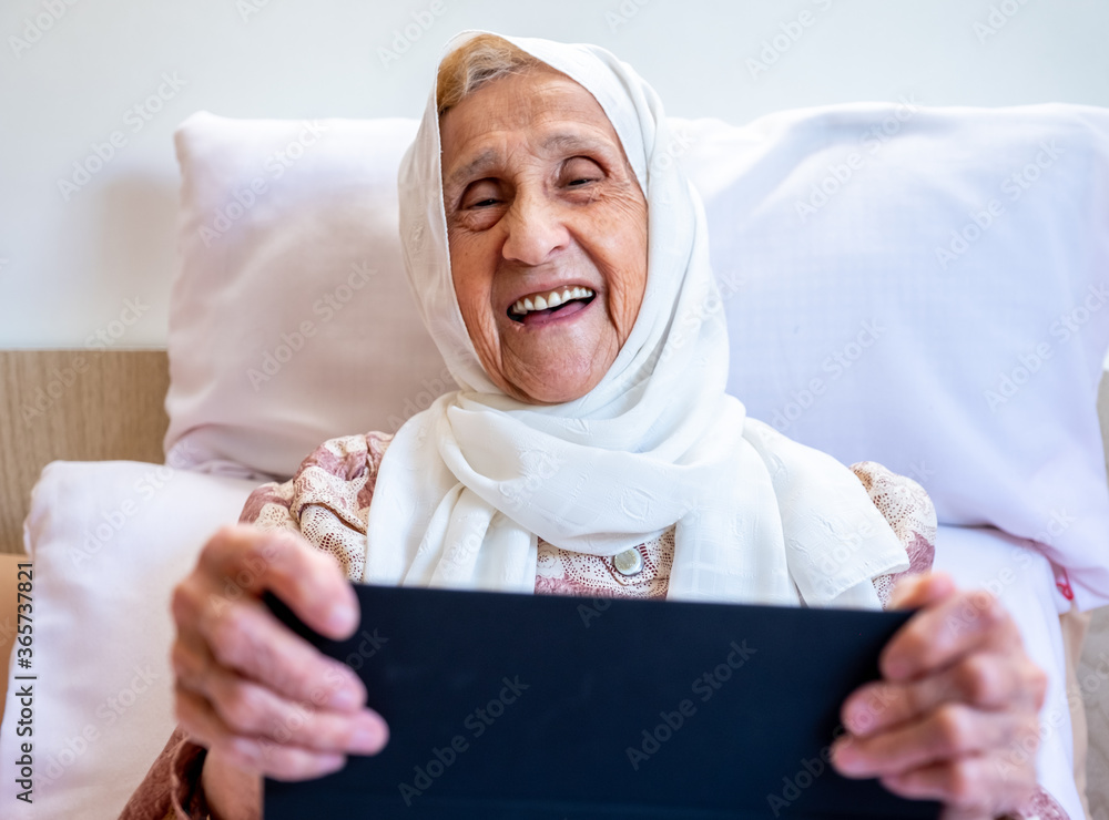 Wall mural Portrait of senior Arabic woman using electronic tablet at home