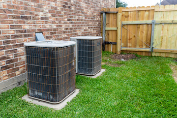 Older air conditioner units next to brick home with copy space