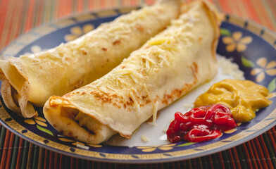 Brazilian pancake rolls stuffed with meat and covered in cheese