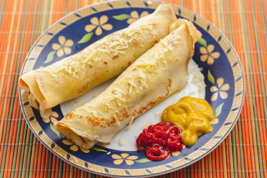 Brazilian pancake rolls stuffed with meat and covered in cheese