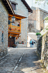 Fototapeta na wymiar Mother and son walking through a beautiful town in the Pyrenees. typical mountain street