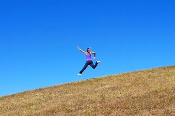 happy young woman jumping from the hill. girl running down the mountain.