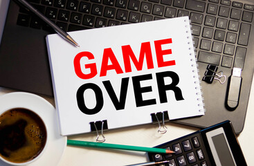 Game Over inscription and word in a notebook near a cup of coffee
