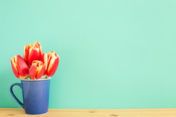Red tulip flowers on wooden table with mint green background. floral arrangement, copy space