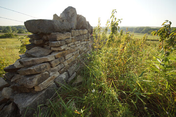 Fototapeta na wymiar An old stone fence in the grass in the Kansas prairie.