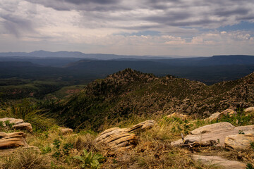Fototapeta na wymiar On this portion of the Mogollon Rim in Arizona, the terrain at the edge is quite rocky and uneven. Close hills can be seen, and in the distance, the valley far below.