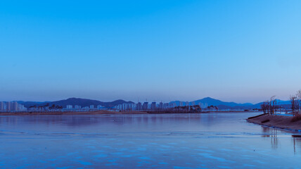 Frozen lake and skyline at blue hour