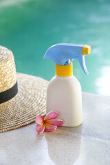 Sunscreen lotion in white blank plastic bottle, straw hat and pink frangipani flower. Summer vacation concept.
