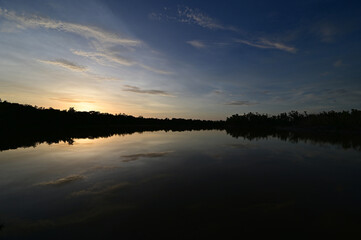 Brilliant colorful clouds in twilight reflected on calm water of Eco Pond in Everglades National Park, Florida on summer evening.
