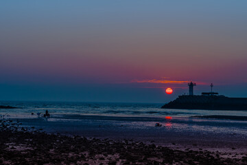 Obraz premium Setting sun behind lighthouse